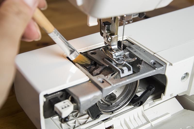 using brush to clean sewing machine